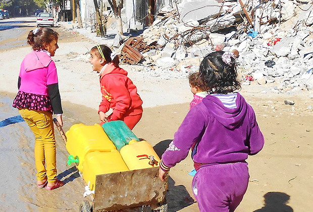 Suha, 10, and Nada, 9, must visit communal water storage tanks daily to fill empty plastic water cans and carry them back to their family homes. Each filled container can weigh up to 44 pounds, a heavy burden for a young child. The need for safe water in Gaza is urgent following extensive damage to water and sewage systems caused by last summer's conflict. IOCC is responding by delivering drinking water to storage tanks in the affected communities. (photo: IOCC)