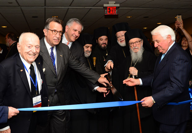 Leadership 100 Chairman, Argyris Vassiliou, third from left, at Ribbon Cutting of Exhibit Hall of 44th Biennial Clergy-Laity Congress, with (L to R) Leadership 100 Founder, Chairman Emeritus and Honorary Chairman of Congress, Arthur C. Anton, Peter Bassett, Co-Chair, Metropolitan Apostolos of Derkoi, Metropolitan Maximos of Selyvria, Host Metropolitan Methodios of Boston, Archbishop Demetrios, and Michael Sophocles, Co-Chair. PHOTO:DIMITRIOS PANAGOS