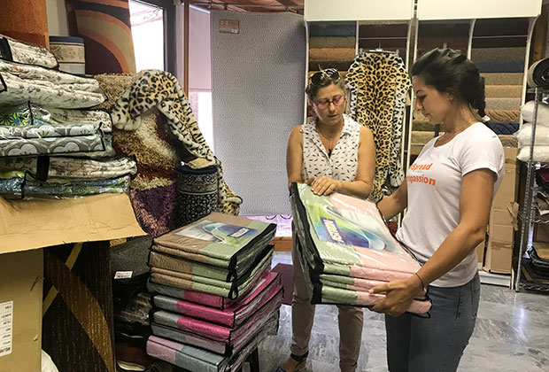 When We Band Together co-founder Zoë Pappis purchases bedding at a local store in Lesvos. WWBT tries to buy aid locally to help the host-community and refugees.