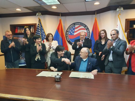 Back row, left to right: Arsen Shirvanyan, Governor Affairs Director ANCA-WR, ANCA-WR Board Member, Alexandra Warren, Vice President of AHC, ANCA-WR Board Member, ANCA-WR Board Member, ANCA-WR Board Member, Christianna Kontou, Executive Director of AHC, ANCA-WR Board Member, Zoi Palla, AHC Board Member, Armen Sahakyan, ANCA-WR Executive Director. Signing at the table, left to right: ANCA Western Region Chairperson Nora Hovsepian, Esq and Dr. James F. Dimitriou, AHC President and Chairman.