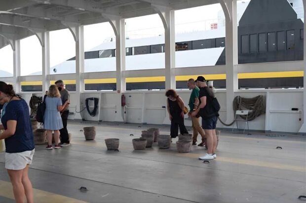 Visitors engage with Eri Dimitriadi’s installation on the ferry deck during the site-specific exhibition about the memory of Agios Georgios island. Photo: Stamatis Koutsoukos